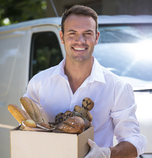 home amb caixa amb pa i productes de pastisseria -Curs de transportistes i distribuïdors alimentaris - Ecotècnic Andorra